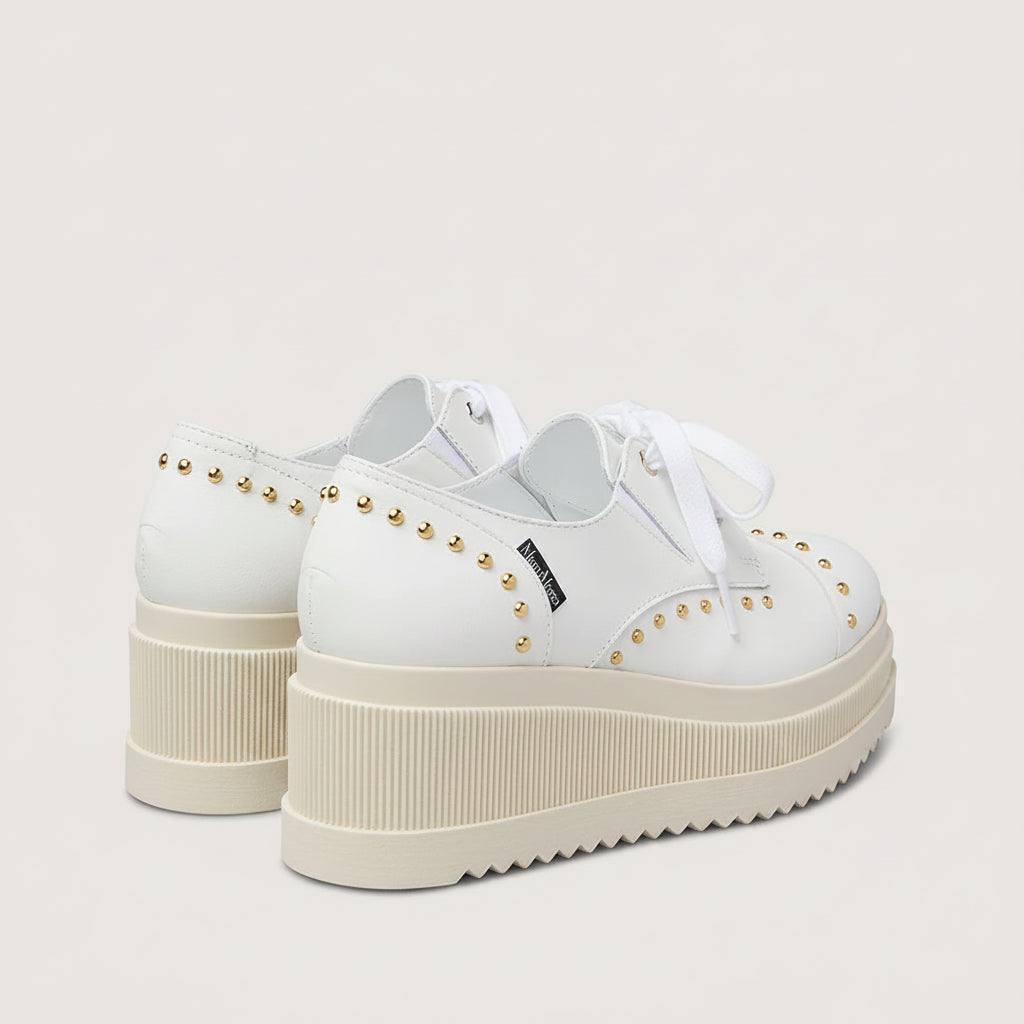 White sneakers with platform sole and studded details on a light gray background