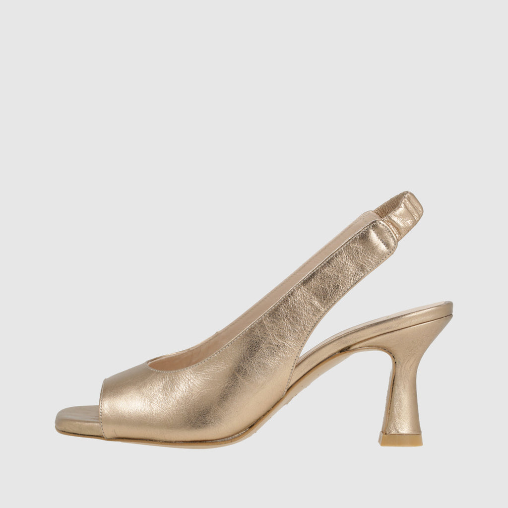 Gold high-heeled shoe on a light gray background