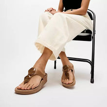 Load image into Gallery viewer, Person wearing brown sandals with decorative straps on a white background
