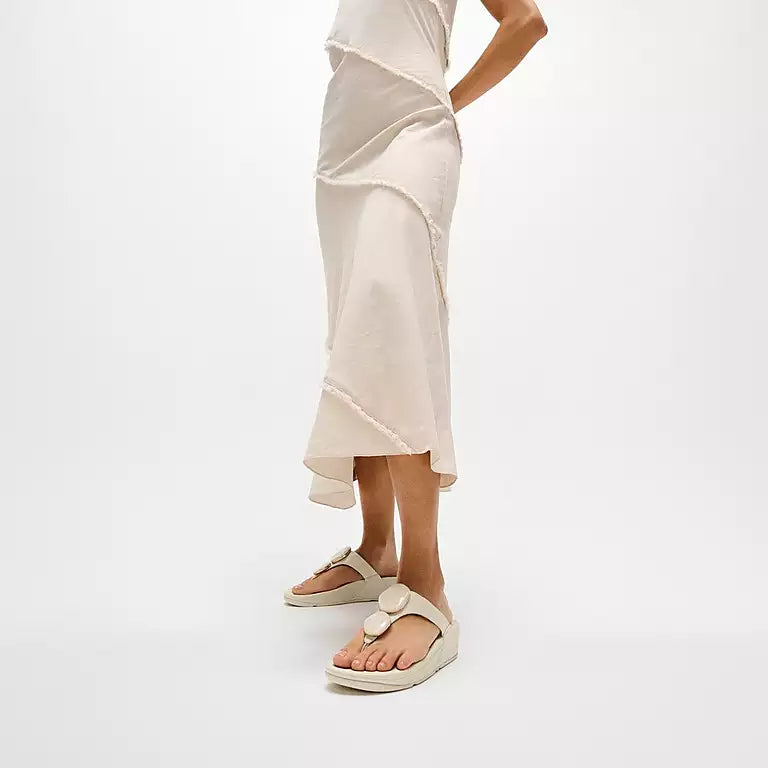 Person wearing a beige skirt and sandals on a white background