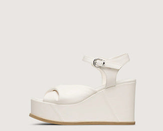 White platform sandals worn by a person on a beige background