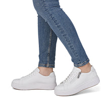 Load image into Gallery viewer, White sneakers worn with blue jeans on a white background
