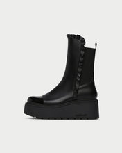 Load image into Gallery viewer, A black leather ankle boot with a chunky platform sole, featuring a ruffled elastic side panel and a small heel pull tab, shown from a side profile on a light gray background.
