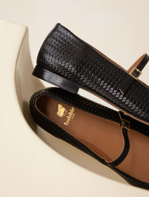 Black woven sandal on a beige background