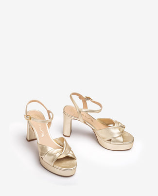 Gold high-heeled sandal on a white background
