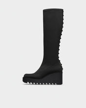 Load image into Gallery viewer, A single black knee-high boot with a chunky wedge platform sole and a row of sharp teeth-like studs running down the outer side, shown in profile against a light gray background.
