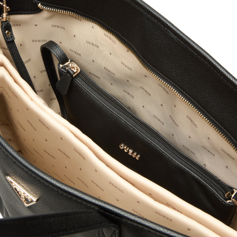 Close-up of a black handbag with visible 'Guess' branding on a beige interior.
