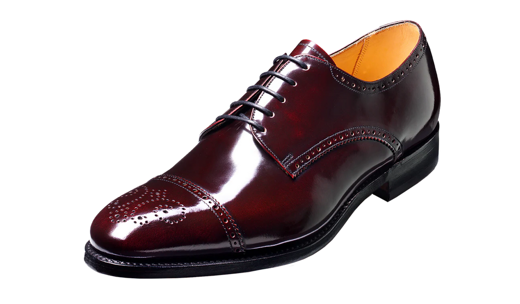 A glossy dark burgundy wingtip oxford shoe with brogue detailing and black laces, shown from a three-quarters angle on a white background.