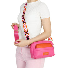 Load image into Gallery viewer, Person holding a pink crossbody bag with an orange interior and colorful strap.
