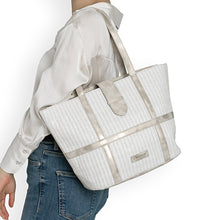 Load image into Gallery viewer, Person holding a white woven tote bag with beige accents on a plain background
