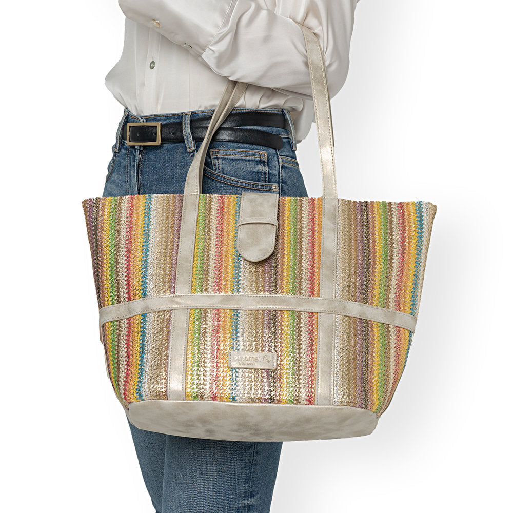 Multicolored striped tote bag held by a person wearing jeans and a white shirt.