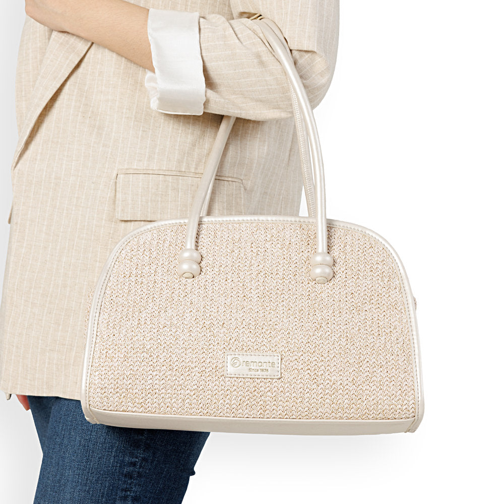 Beige textured handbag held by a person wearing a beige coat and blue jeans on a white background