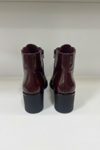Load image into Gallery viewer, A pair of women's ankle boots in glossy dark burgundy leather with chunky black block heels, shown from the back on a white surface against a white background.
