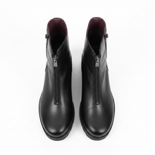 Load image into Gallery viewer, A pair of black leather ankle boots with side zippers, shown from the front on a plain white surface against a white background.
