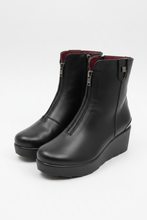 Load image into Gallery viewer, A pair of black leather ankle boots with wedge heels and side zippers, photographed on a plain light background.
