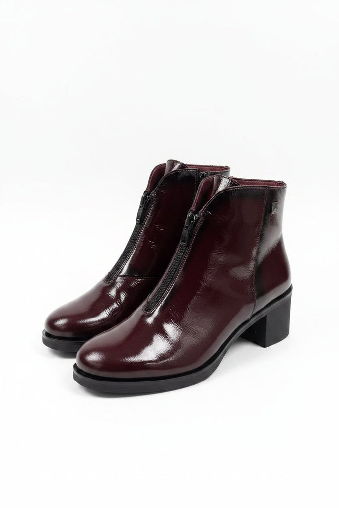 A pair of women's ankle boots in glossy deep burgundy patent leather with black block heels and side zippers, shown against a plain light gray background.