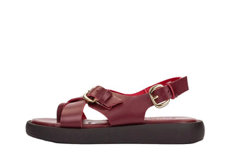 Red sandal with a gold buckle on a light gray background