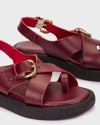 Red sandal with a gold buckle on a light gray background
