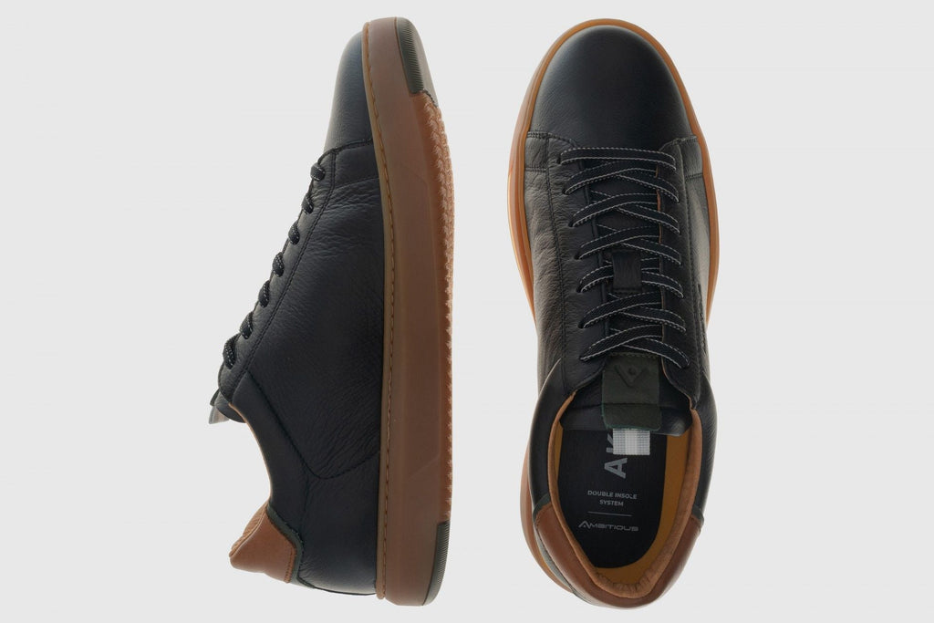 Black leather shoes with brown soles on a light gray background