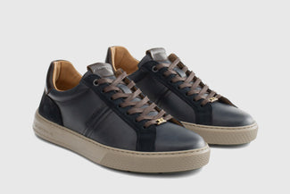 Navy blue sneaker with beige sole on a light gray background