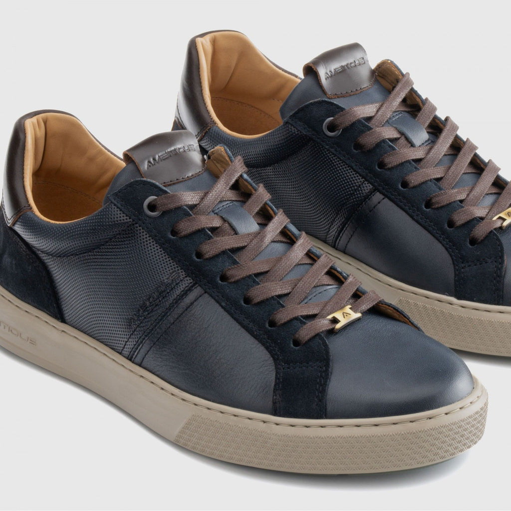 Pair of blue sneakers with brown laces on a light gray background