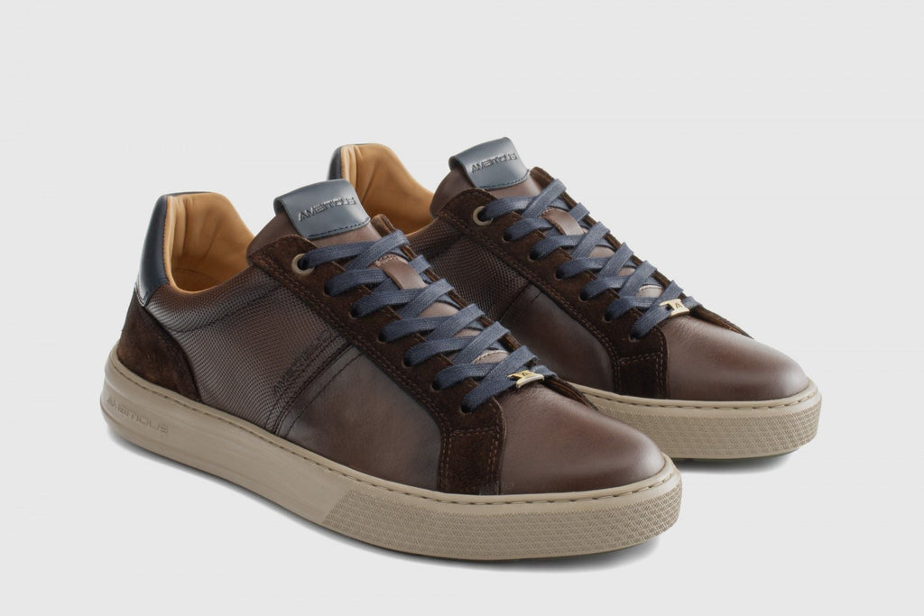 Pair of brown sneakers with beige soles on a light gray background