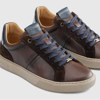 Brown sneaker with beige sole on a light gray background