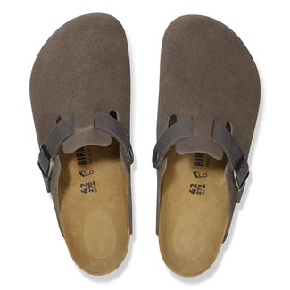 Brown suede clog shoe with a single buckle on a white background
