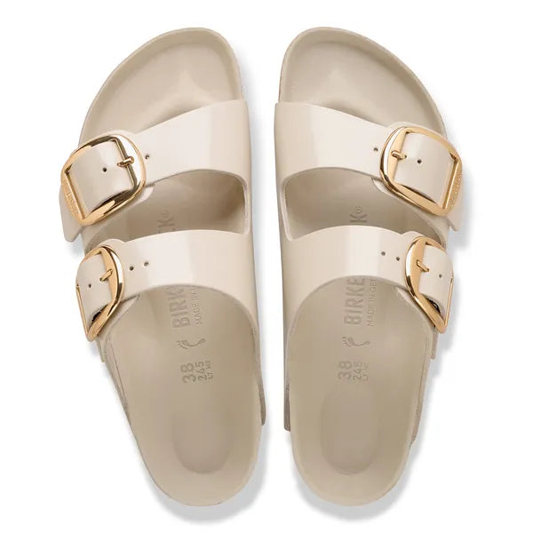 Beige sandals with gold buckles on a white background