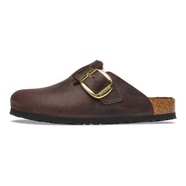 A dark brown leather clog shoe with a gold buckle strap and a cork heel, shown in a side profile on a white background.