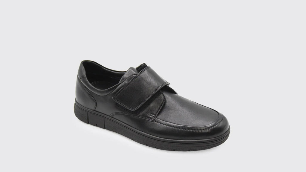 Black leather shoe with velcro straps on a white background