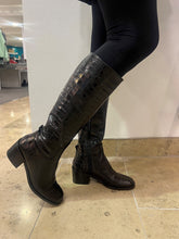 Load image into Gallery viewer, Person wearing black knee-high boots with a textured pattern on a tiled floor.
