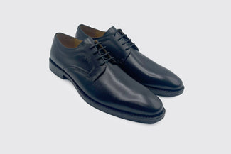 Black  leather shoe on a light gray background