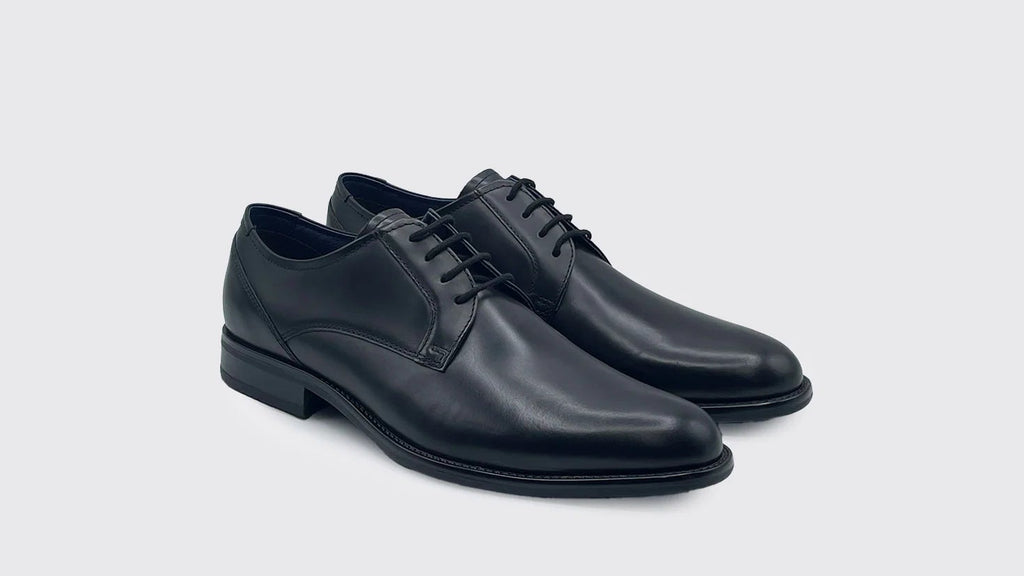 Pair of black leather dress shoes on a light gray background