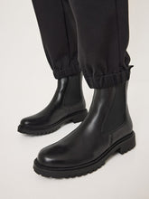 Load image into Gallery viewer, Black leather boots worn with black pants on a light gray background
