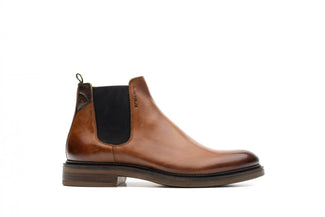 Brown leather Chelsea boot with black patch on a white background