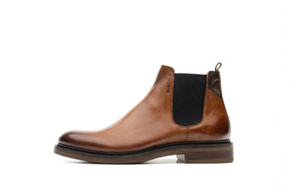 Brown leather Chelsea boot with black patch on a white background