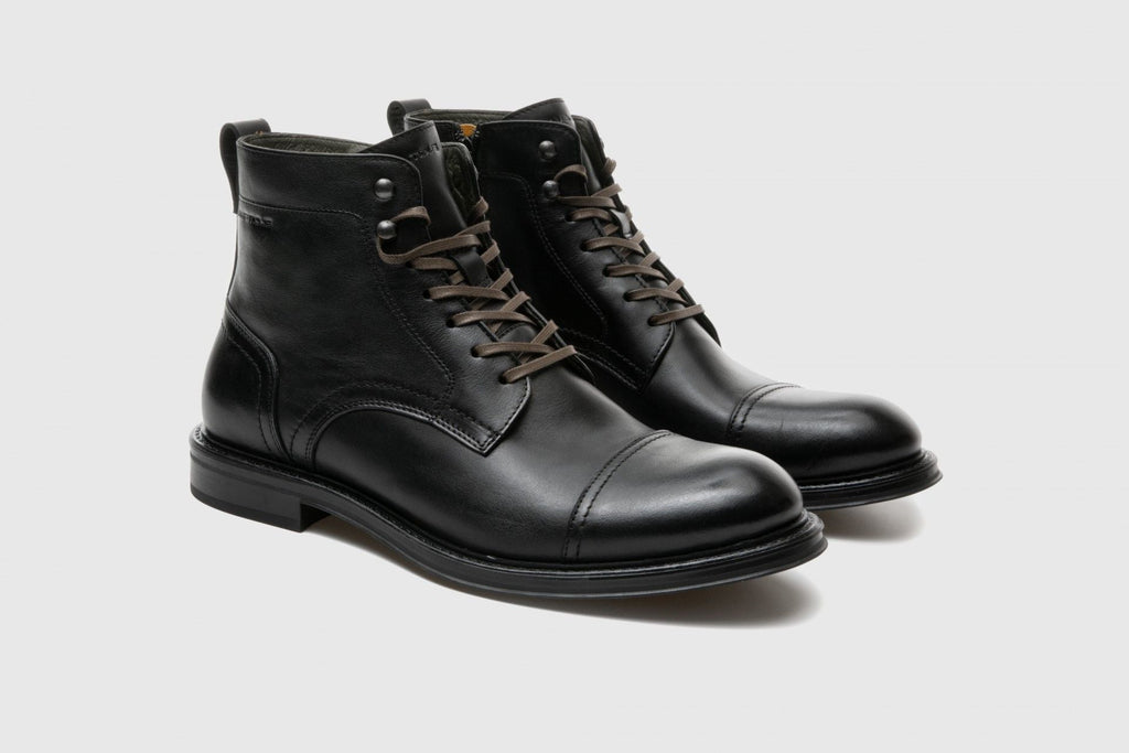 Pair of black leather boots on a light gray background