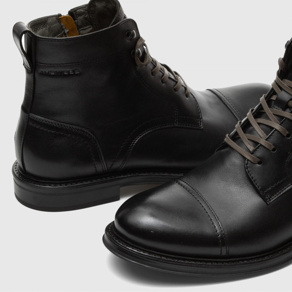 Pair of black leather boots on a light gray background