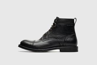 Black leather boot on a light gray background