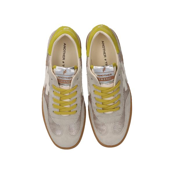 Pair of white sneakers with yellow accents on a white background