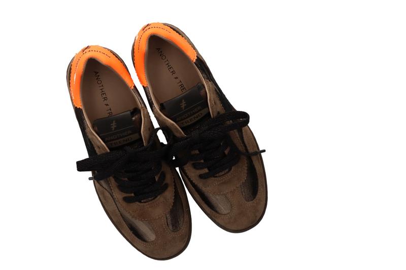 Pair of brown shoes with orange soles on a white background