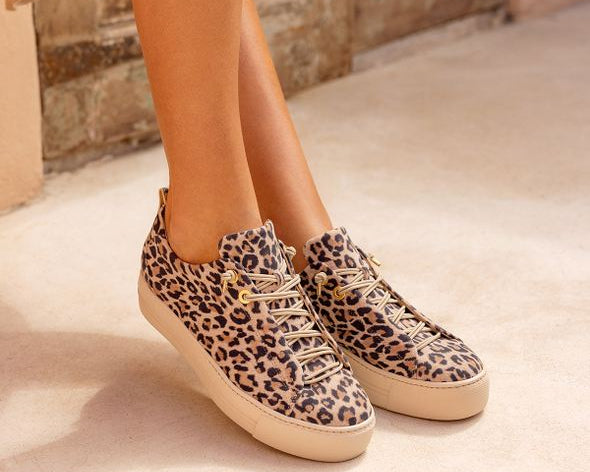 Leopard print sneakers worn indoors on a neutral background