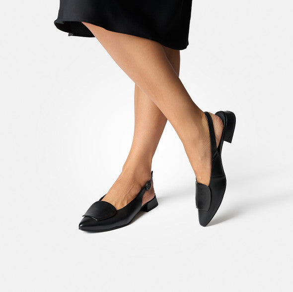 Black slingback shoes worn with a black skirt on a white background