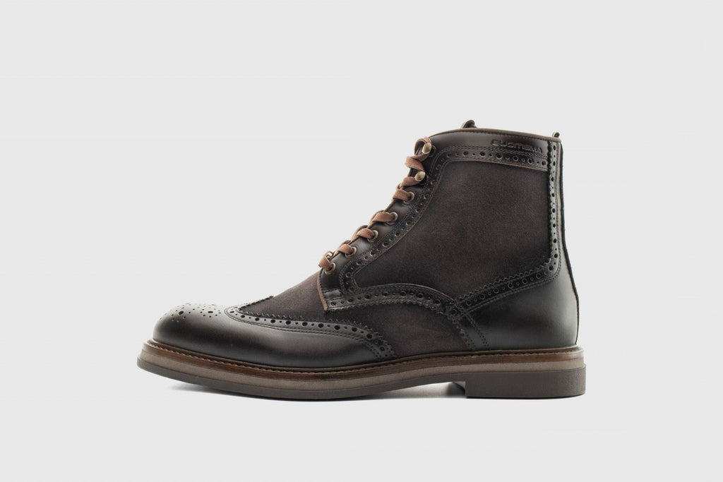 Black leather wingtip boot on a light gray background