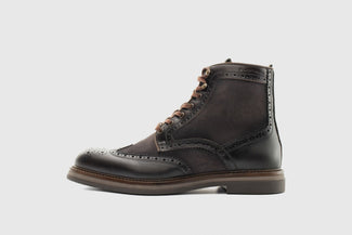 Black leather wingtip boot on a light gray background