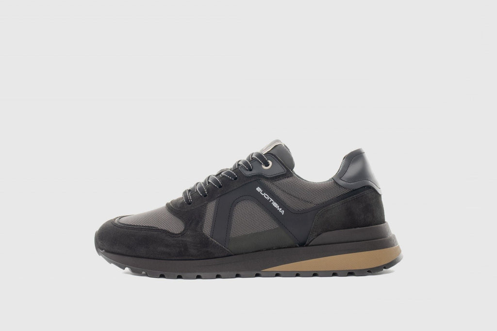 Black sneaker with brown sole on a light gray background
