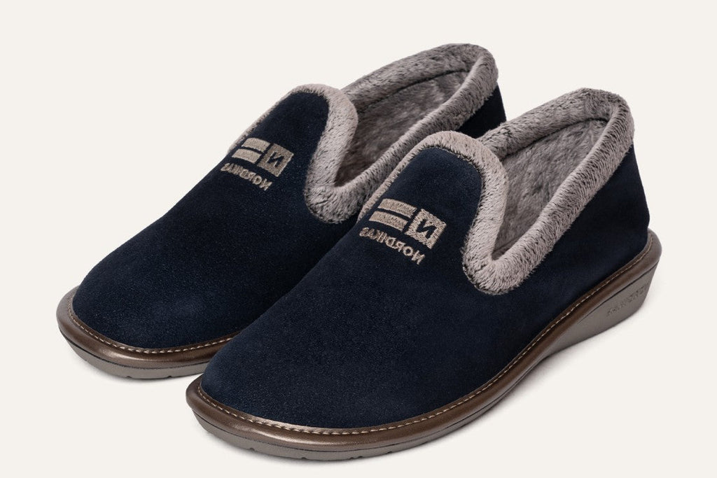 Pair of navy blue slippers with gray interior on a white background