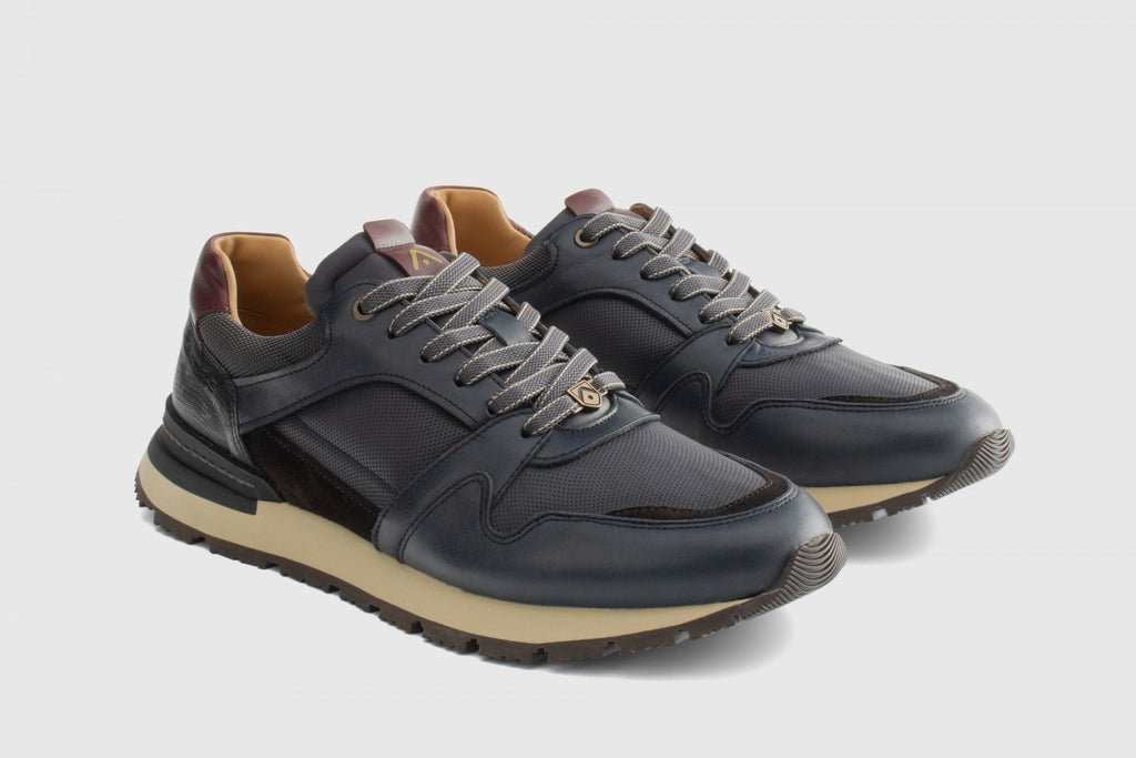 Pair of dark blue sneakers with beige accents on a light gray background