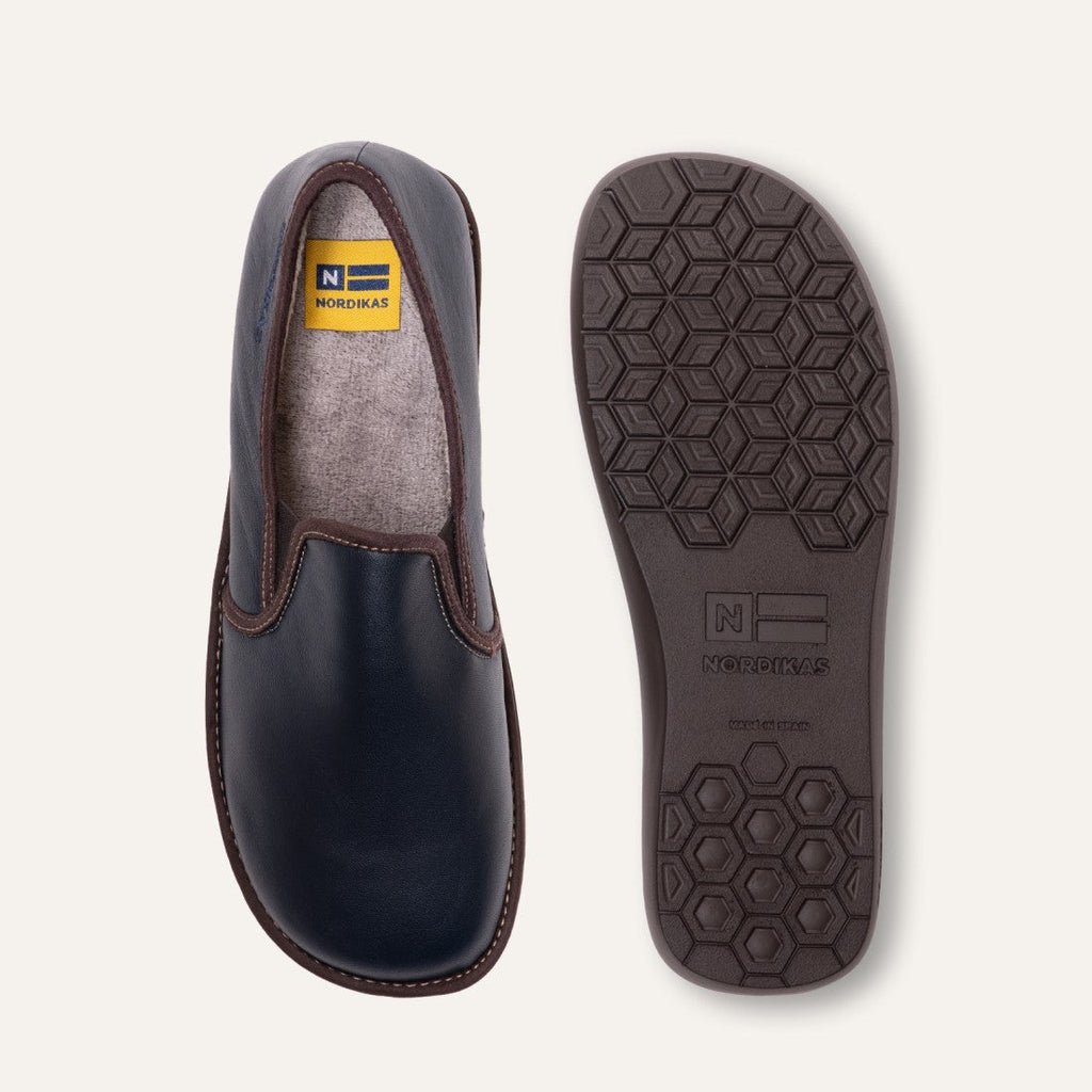 Black slip-on shoe with brown accents and a visible brand logo on a light gray background